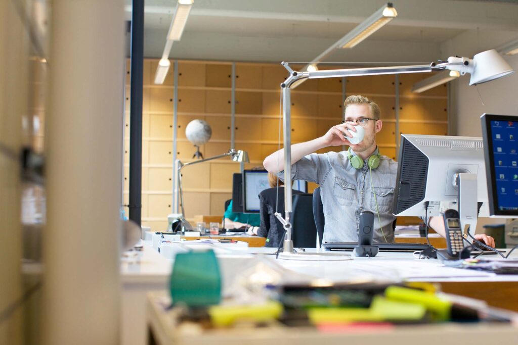 young-man-drinking-coffee-at-office-desk-3926DV7.jpg